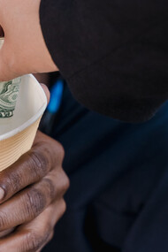 Mão doa um nota de dinheiro para pessoa desempregada e em situação de desabrigo