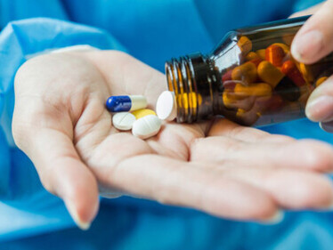 A woman’s hand gently pours pills from a medicine bottle
