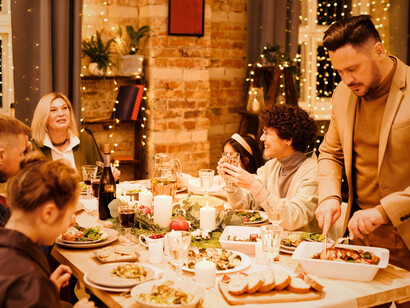 A family sharing food and laughter, reflecting the heart of Christmas celebrations across nations