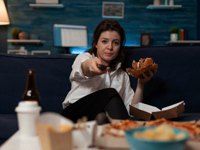 A woman enjoys a binge-eating session on the couch while watching her favorite show