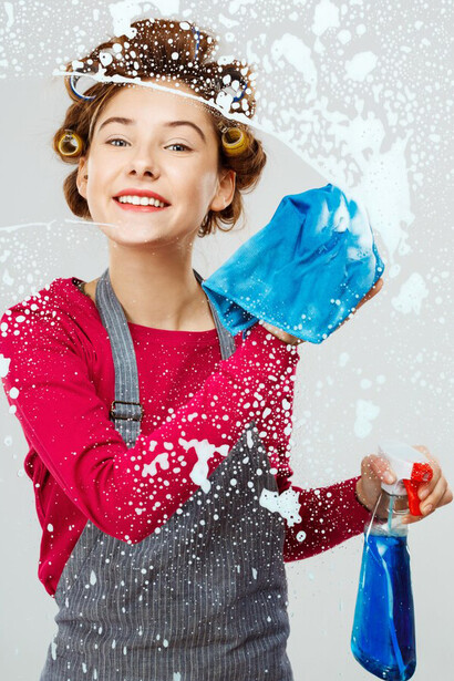 A young woman cleans windows during her spring cleaning, using supplies to declutter and create an organized, fresh space in her home