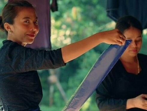 Two women looking at textiles together, representing the way Baduy women pass down motifs, meaning, and craftsmanship