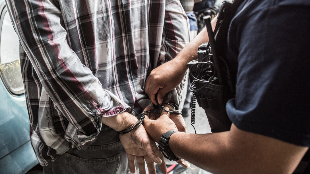 An individual is placed in handcuffs by an officer of US Immigration and Customs Enforcement