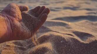 A hand pouring sand out, reflecting how peace sometimes requires us to loosen our grip on old troubles