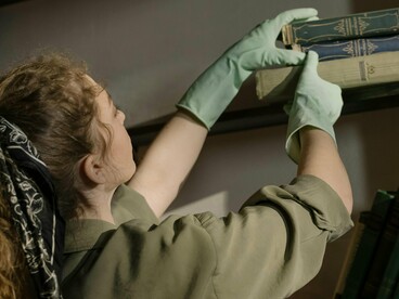 Une femme organise et nettoye l'étagère aux  livres