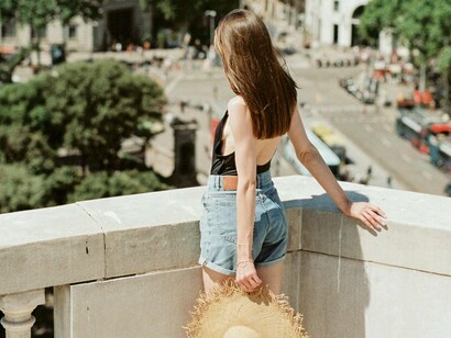 Mulher aproveita verão em Barcelona, Espanha. Começam os festivais de músicas e gastronomia, festas aguardadas durante o ano todo, os casacos guardados e as cangas de praias retiradas para uso quase diário. Com os dias longos, as praias se enchem até mais tarde, se não para pegar um bronze, todos correm pra admirar o pôr do sol, seja no calçadão ou numa mesa da esplanada. O país todo vibra. Assim como no Porto, as demais cidades de todo o continente europeu celebram o tão aguardado verão