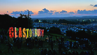 The Glastonbury Festival 2011 captured at night, glowing with lights, music, and the energy of thousands of festivalgoers
