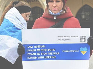 Una donna regge uno striscione che chiede la fine della guerra e dichiara il suo sostegno all’Ucraina