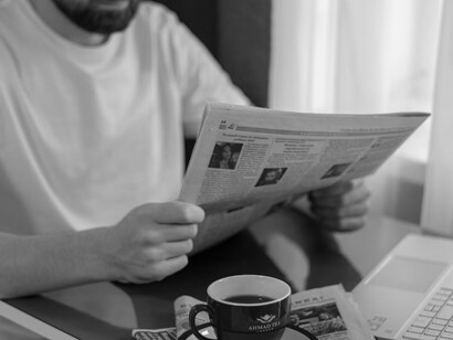 A man sitting at a desk, reading a newspaper, contemplating how AI is shaping journalism and its impact on the concept of truth in media