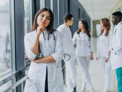 A female doctor giving a thumbs-up gesture while standing in the hospital corridor, symbolizing positive medical ethics and patient care