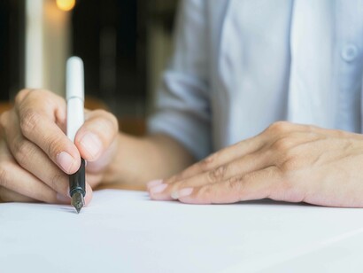 Una persona scrive con una penna stilografica su un foglio di carta bianco