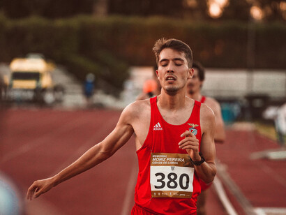An athlete in a red tank top runs with his eyes closed during an Olympic race