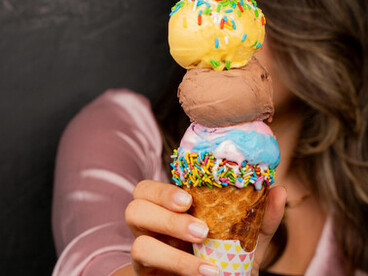 A woman’s hand holding an ice cream cone topped with sugar sprinkles