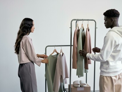 A stylish couple exploring a boutique, touching neatly arranged minimalist garments