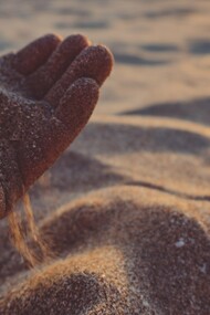 A hand pouring sand out, reflecting how peace sometimes requires us to loosen our grip on old troubles