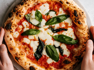 A devotee of the Holy Pizza lifts a slice, ready for the first bite