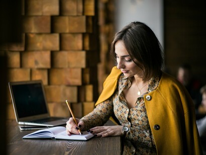 A woman writing in her book, capturing the emotional labour of turning writing from a hobby into a lifelong commitment