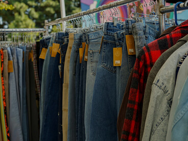 A close-up view of pre-loved garments on a clothing rack at a flea market, reflecting the growing presence of secondhand fashion