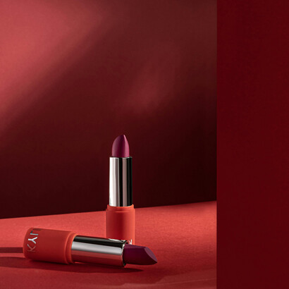 A sleek, luxurious lipstick stands out beautifully on a bold red background