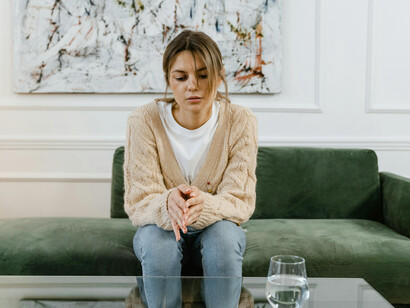 A sad woman sitting on a sofa, representing anxiety and mental health struggles