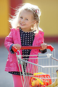 A happy, smiling child shopping with a cart, learning about ingredients and choosing healthy food