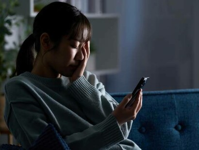 A depressed woman staring at her smartphone, scrolling through social media apps like TikTok and Instagram Reels, overwhelmed by digital anxiety