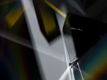 Un prisma verticale disperde la luce in un vivido arcobaleno su sfondo nero