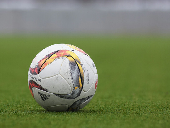 An Adidas soccer ball resting on the grass pitch, ready for the game