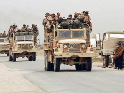 A convoy of Iraqi KM25 (6×6) 2,500-kg cargo trucks carrying Free Iraqi Forces (FIF) soldiers travels along a highway in An Nasiriyah, Iraq, en route to join coalition forces during Operation Iraqi Freedom