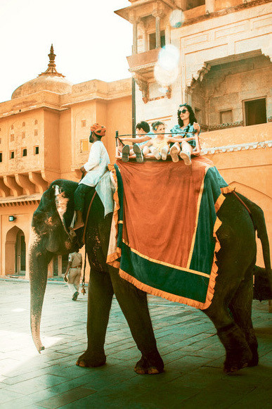 In Jaipur, India, a man and woman ride an elephant against the backdrop of a colorful building