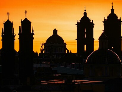 Silhouettes of church bell towers and domes against a golden sunset sky, Mexic0