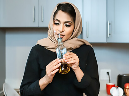 With health in mind, a woman holding olive oil is readying herself to cook a wholesome meal