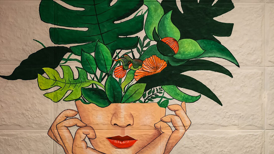 A painting of a girl with green and red flowers emerging from her head, symbolizing the concept of love as a force for personal growth and mental health