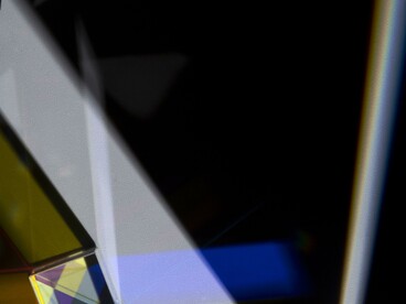 Fascio di luce bianca colpisce un prisma, creando un intenso raggio bluastro