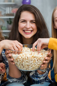 Enjoying quality time, friends gather to watch a TV series, indulging in popcorn snacks for a delightful viewing experience