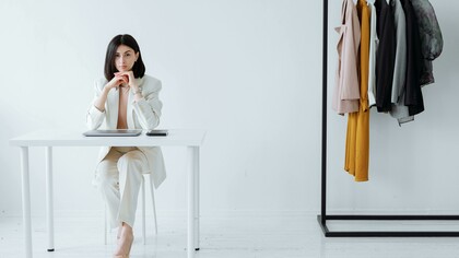 A stylist sitting at a desk in a fashion store, preparing looks and assisting clients