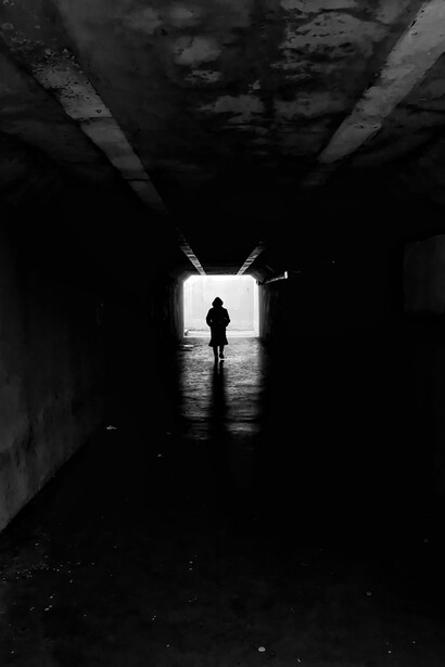 Silhouette of a person walking through a dark tunnel toward the light, symbolizing the search for purpose and inner clarity