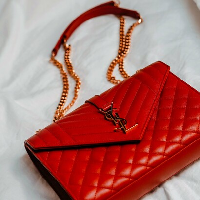 A stunning red quilted YSL bag with a gold chain, an example of the score high-end pieces you can score at your local thrift shop