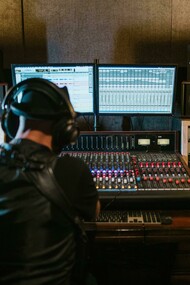 Editor de som trabalha em seu estúdio. No Brasil, o panorama da dublagem ainda é marcado por uma falta de união e maturidade frente às transformações tecnológicas. Porém, esse desafio não é apenas brasileiro, mas aqui se manifesta em um ambiente onde decisões são muitas vezes baseadas em relacionamentos pessoais, egos e interesses regionais, como entre São Paulo e Rio de Janeiro. Isso cria um cenário de fragmentação que atrapalha o desenvolvimento de estratégias coletivas capazes de proteger os profissionais da dublagem e regulamentar o uso da IA