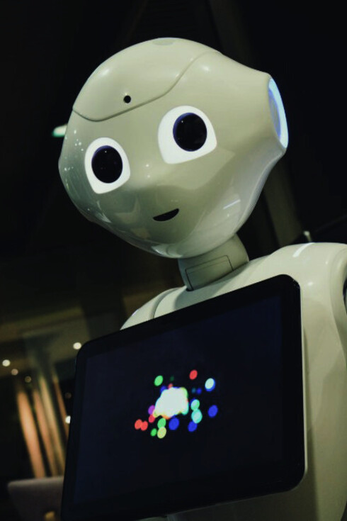 A white robot toy holding a black tablet