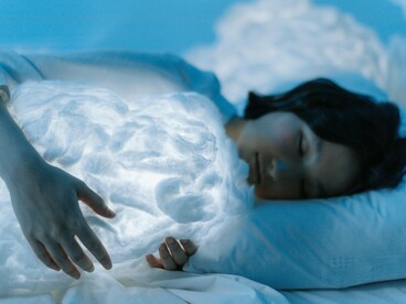 A woman resting, holding a cloud-like ball in her arm, emphasizing the importance of quality sleep