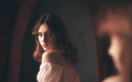 A woman looking at her reflection, representing the curiosity about one's appearance that always exists