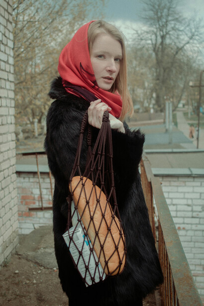 A woman in a black fur coat holding a loaf of bread in a Soviet city, Russia