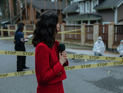 A reporter dressed in red delivering news from a crime scene