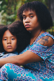 A woman and her daughter sitting on grass