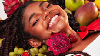 A smiling girl surrounded by colorful Brazilian fruits