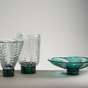 Thick uncoloured glass vase in the shape of an inverted truncated cone.Cylindrical vase in thick uncoloured glass. ‘Leaf’-shaped relief decorations in uncoloured glass and cylindrical foot. Fruit-stand with thick uncoloured glass cup. ‘Leaf’-shaped relief decorations in greenish glass and cylindrical base covered by uneven tesserae in greenish glass. 1933
