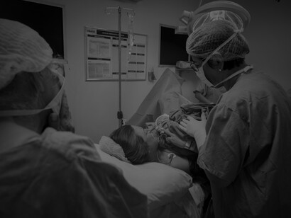 Grayscale image of a doctor with a newborn in the operating room after a cesarean delivery