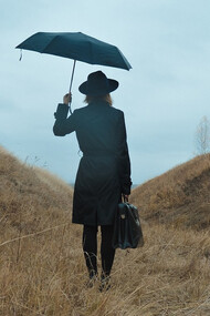 A woman with a suitcase in her hand standing on a path