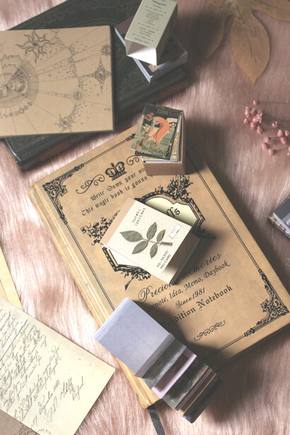 Aesthetic flat lay of a vintage journal or scrapbook with yellowed pages and dried flowers on a wooden table